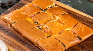 Pizza Delight: Tonino crepe cut into bite-sized squares on a wooden board